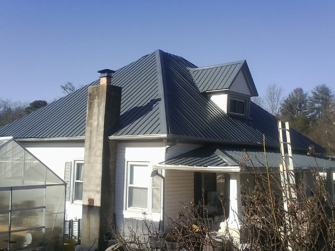 Dark blue standing seam metal roof on a white farmhouse with dormer — Slate & Tile Roof Repair by Roofing Brothers in Norway