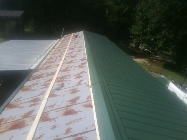 Old rusted panels beside newly installed green metal roofing — Wind Damage Roof Repair by Roofing Brothers in Norway